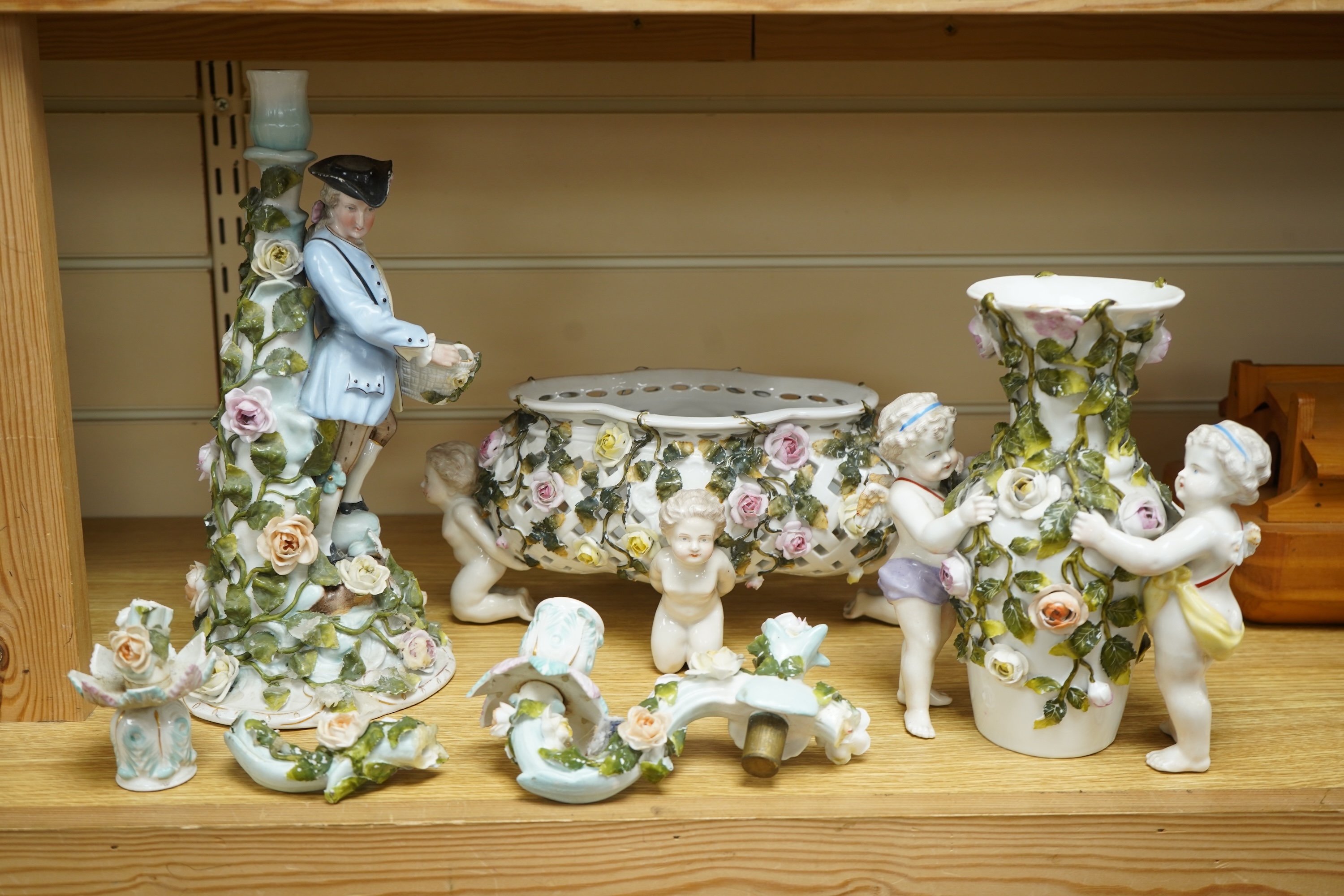 A German flower encrusted porcelain figural candelabrum, 30cm high, a cherub jardiniere and a cherub vase, all encrusted